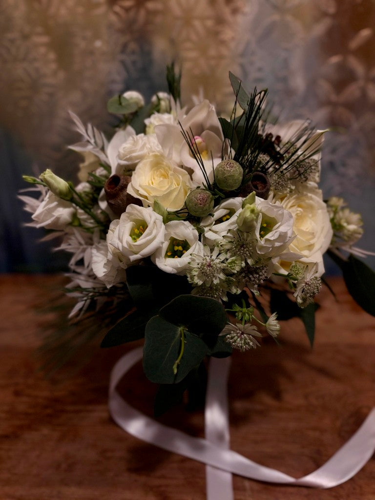A bridal bouquet in shades of cream green and white designed for a wedding in winter