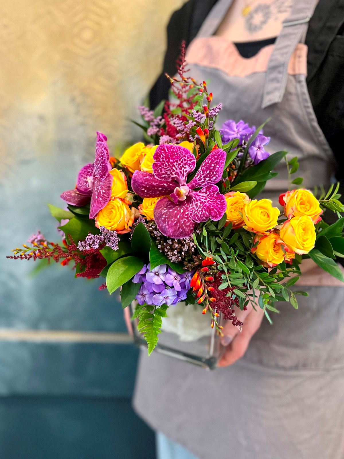 A colourful display of seasonal blooms and foliage arranged in a clear glass vase