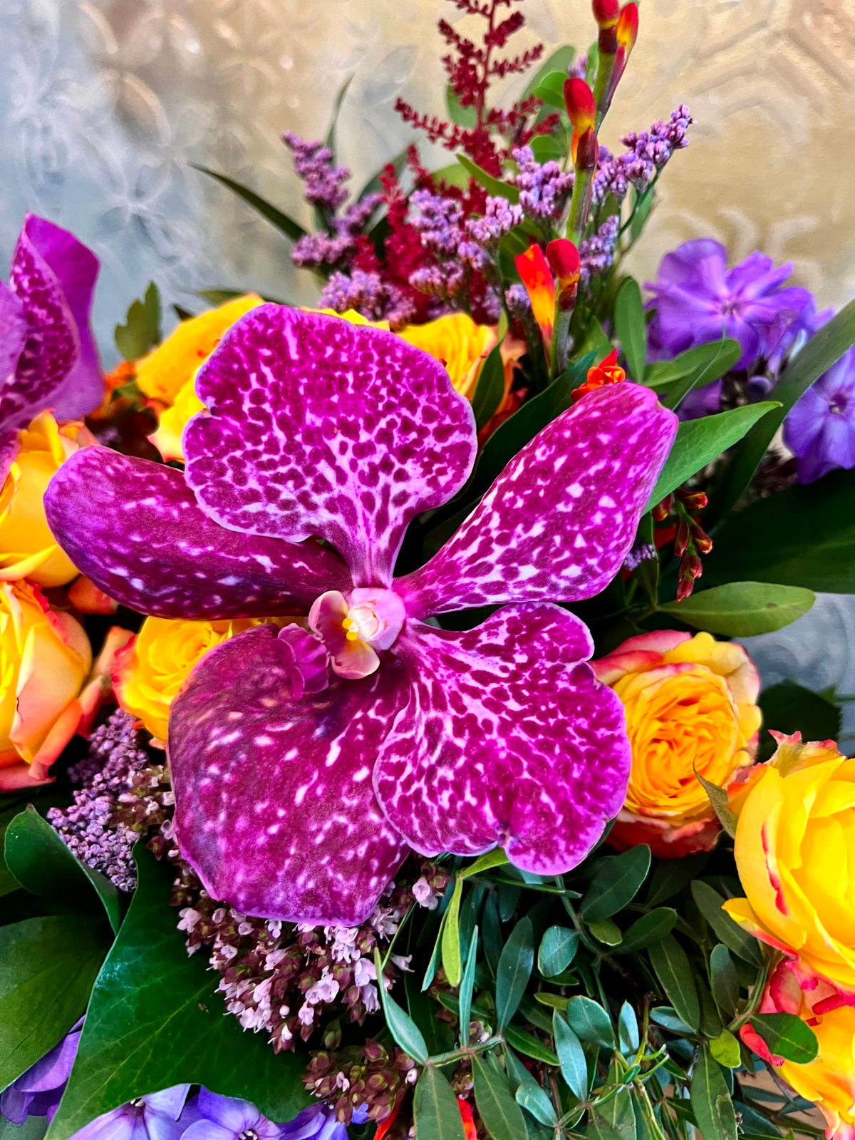 A colourful display of seasonal blooms and foliage arranged in a clear glass vase