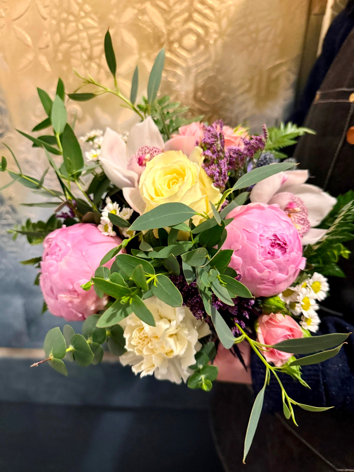 Peony roses flower arrangement in cube vase being held by florist