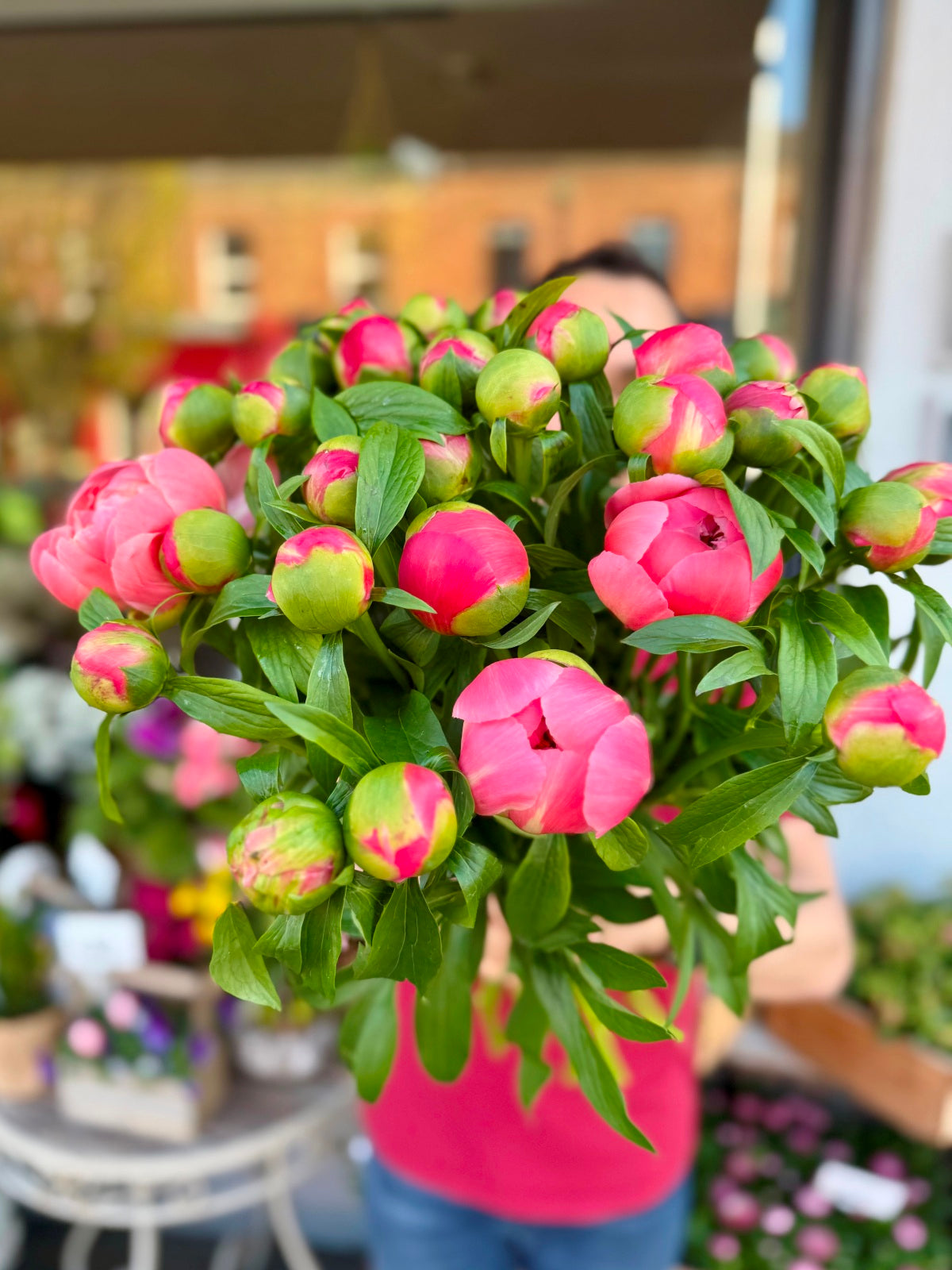 Coral peony rose flower bouquet being held up by one of our florists