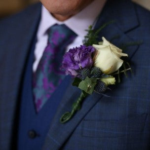 Button hole flower arrangement in a purple colour