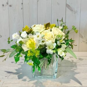 flower arrangement set in a clear glass vase using flowers in cream and green tones