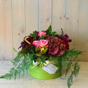 flowers in pinks and reds set in a pretty hatbox. Flower delivery available in Dublin