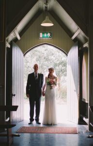Bride with her custom designed wedding flower bouquet entering church with her father