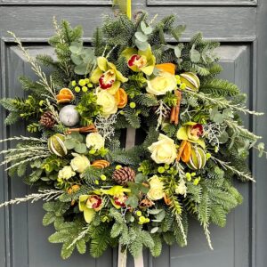 A festive Christmas door wreath hand made by our florists in Ranelagh featuring green foliage and fresh flowers in shades of oranges and lemons