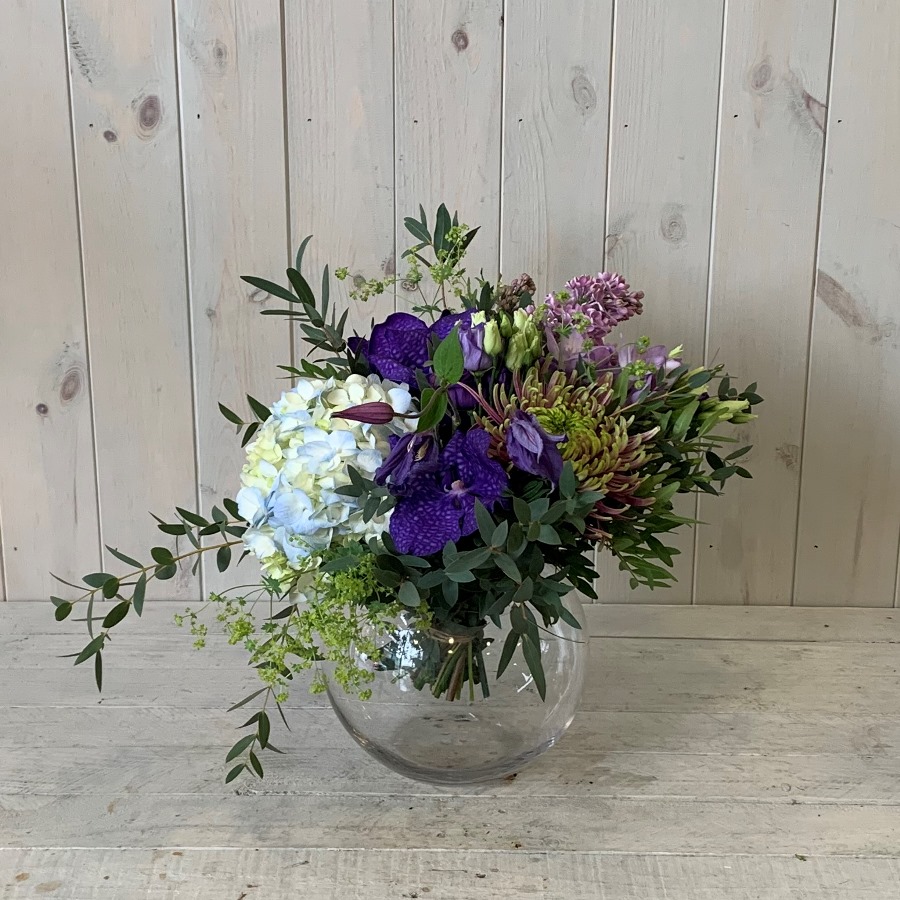 A blue summer themed flower bouquet set in a goldfish bowl vase for delivery in Dublin