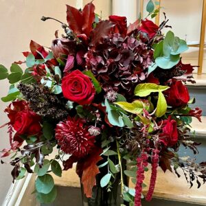 A luxury hand tied bouquet of mixed seasonal flowers in reds with foliage. Designed and delivered in Dublin by Blooming Amazing Flower Company Ranelagh