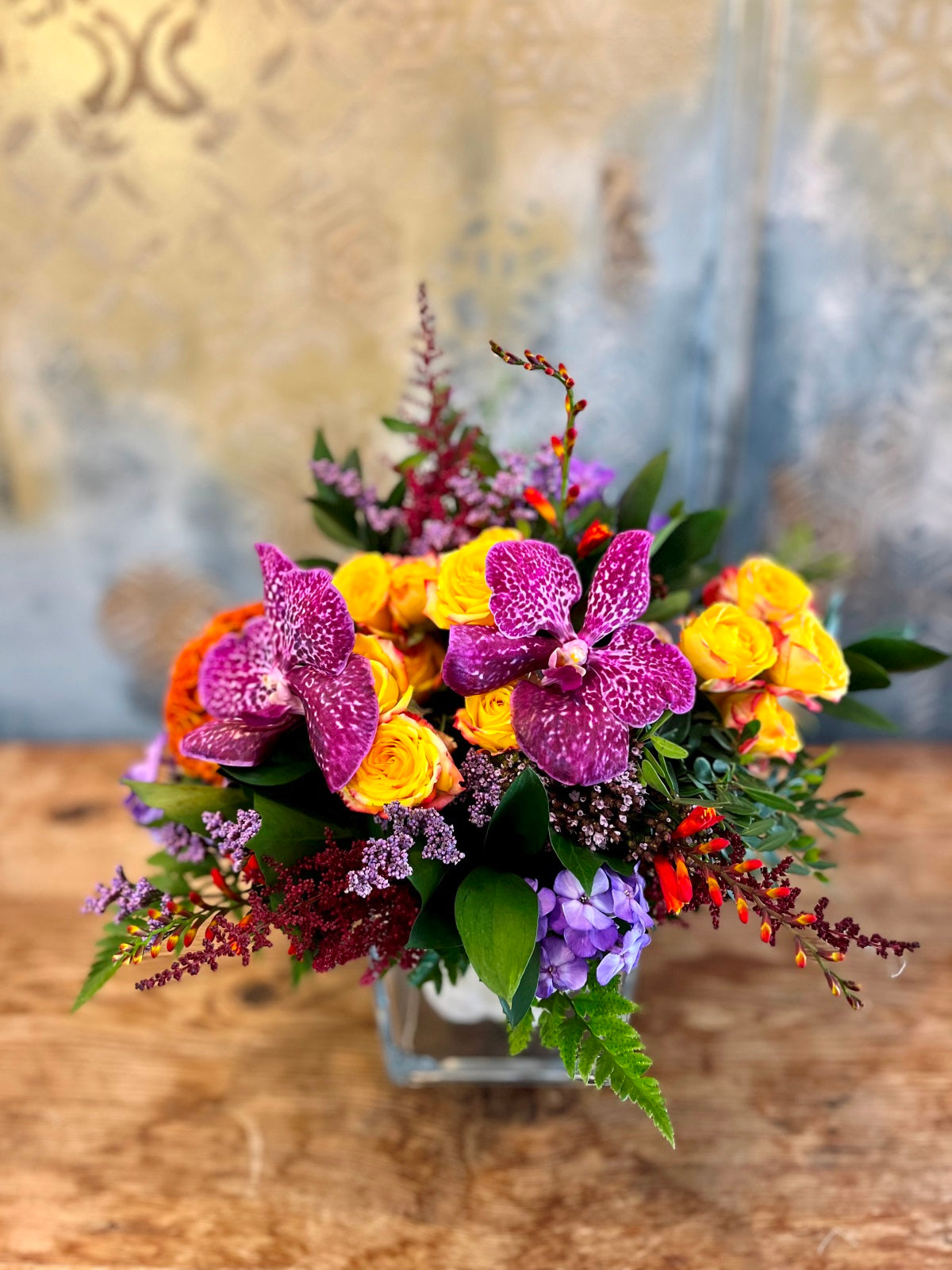 A colourful display of seasonal blooms and foliage arranged in a clear glass vase